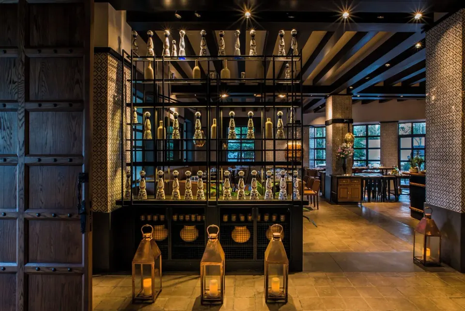 Interior display of illuminated bottles and lanterns in a dim restaurant space at Unico Hotel Riviera Maya