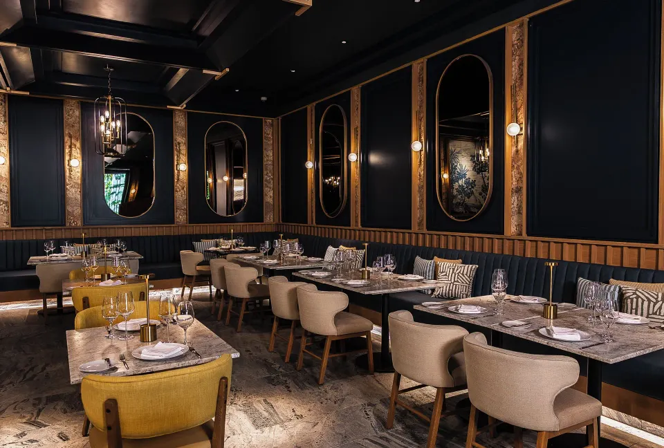 Dimly lit fine-dining room with navy walls and mirrors at Unico Hotel Riviera Maya