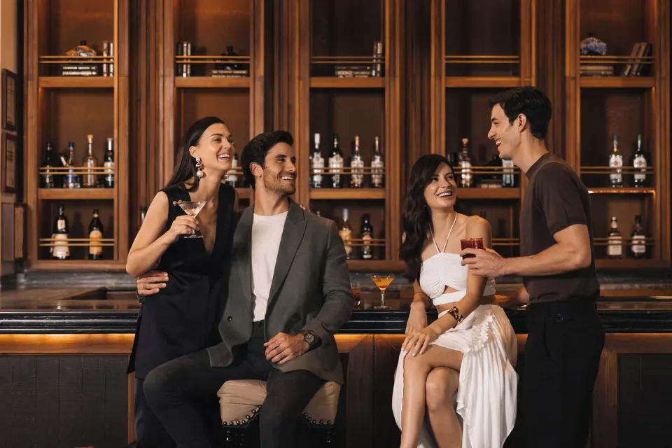 Four people socializing at a polished bar counter at Unico Hotel Riviera Maya