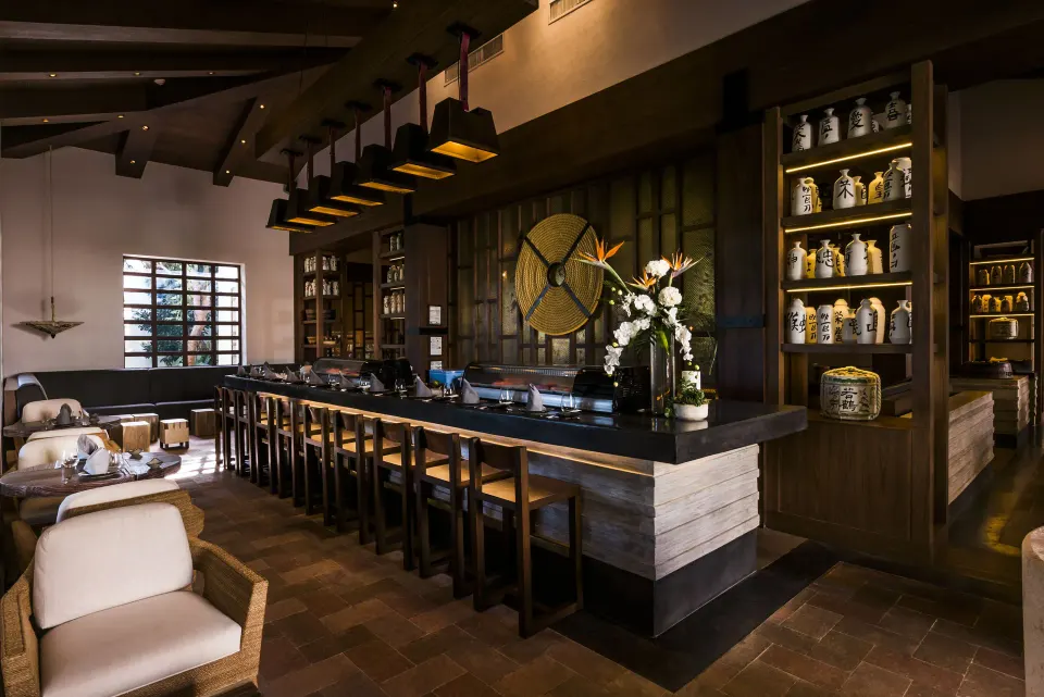 Long interior bar with high stools and decorative jars at Unico Hotel Riviera Maya