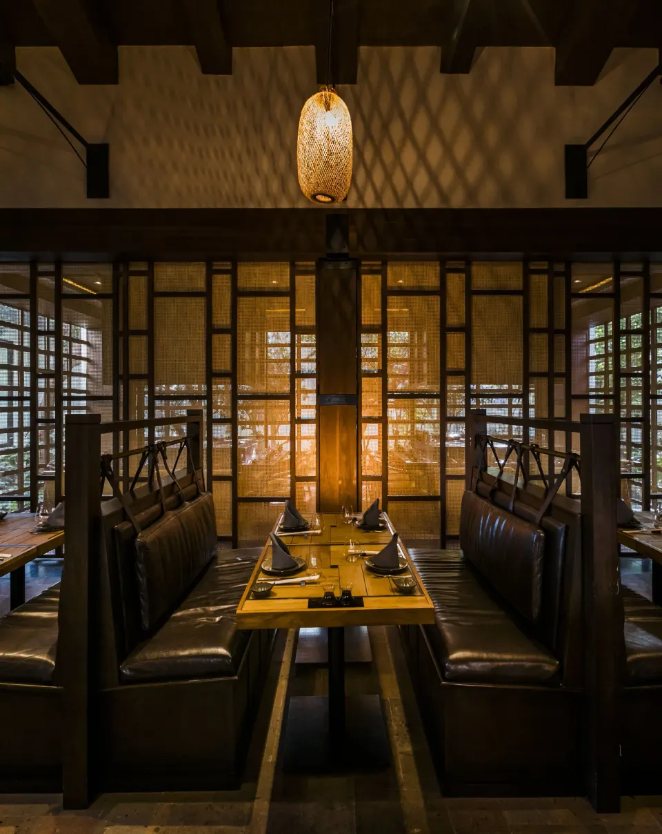 Dark wood booth seating with lantern light at Unico Hotel Riviera Maya