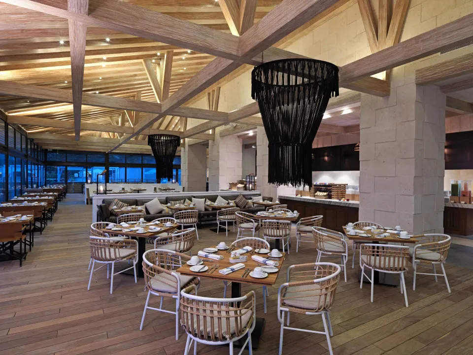 Large open dining room with wooden tables and rattan chairs at Unico Hotel Riviera Maya