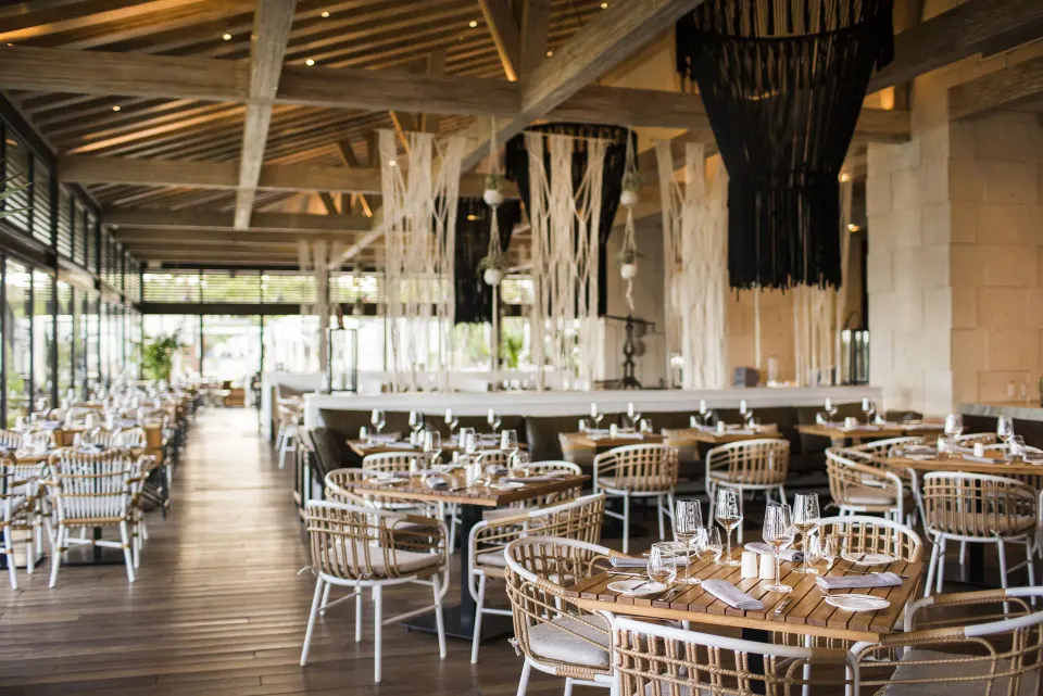 Large airy restaurant dining room with woven chairs at Unico Hotel Riviera Maya