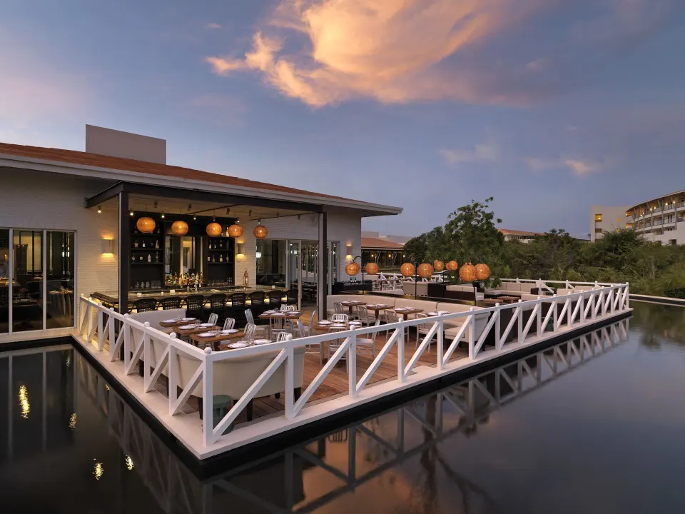 Waterfront outdoor dining deck with lanterns at Unico Hotel Riviera Maya