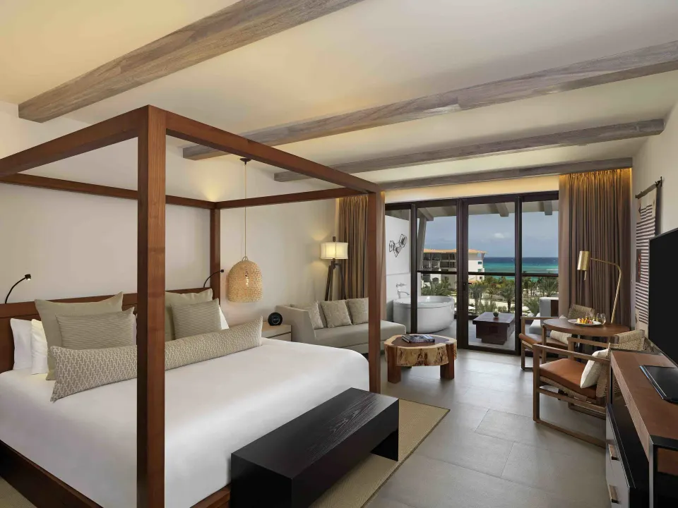 Four-poster king bed and seating area with balcony view in an Alcoba Ocean View room at Unico Hotel Riviera Maya