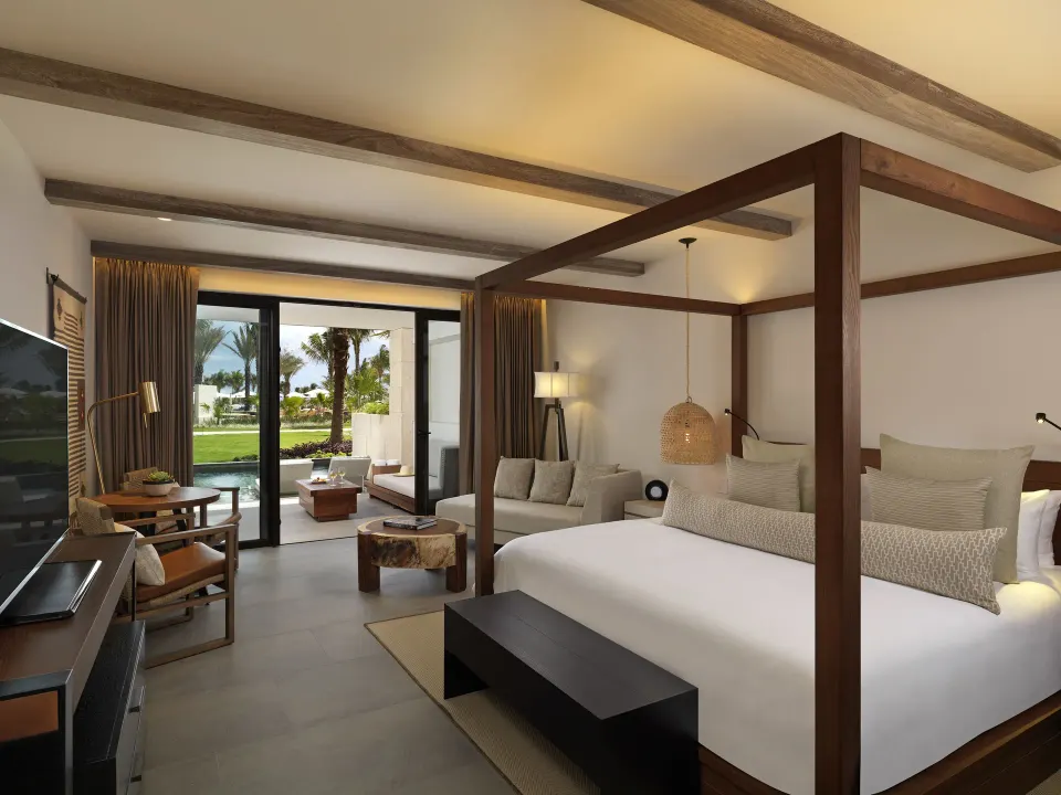 Four-poster Alcoba Swim-up Pool Room interior with seating and sliding doors at Unico Hotel Riviera Maya
