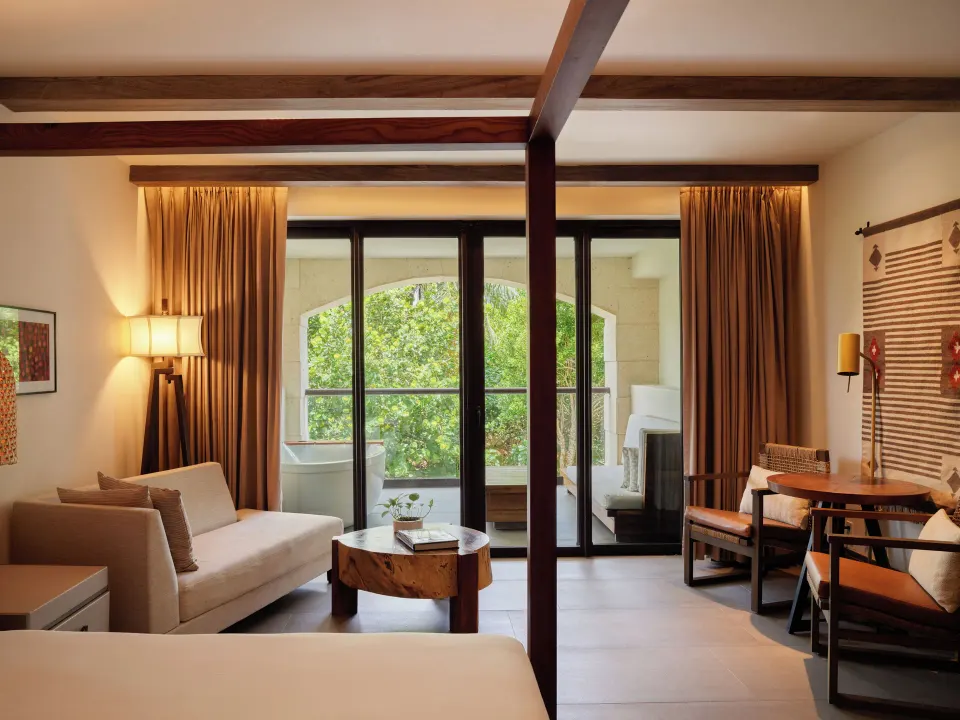 Alcoba Tropical View Room interior with sofa, table and balcony at Unico Hotel Riviera Maya