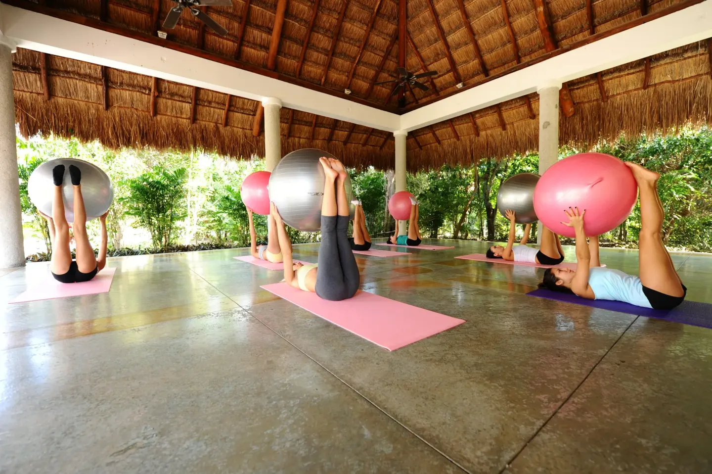 Guests do exercise-ball stretching in an open pavilion at Valentin Imperial Riviera Maya.