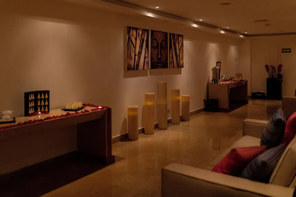 A dim spa lounge with candles, art, and cushioned seating at Valentin Imperial Riviera Maya.