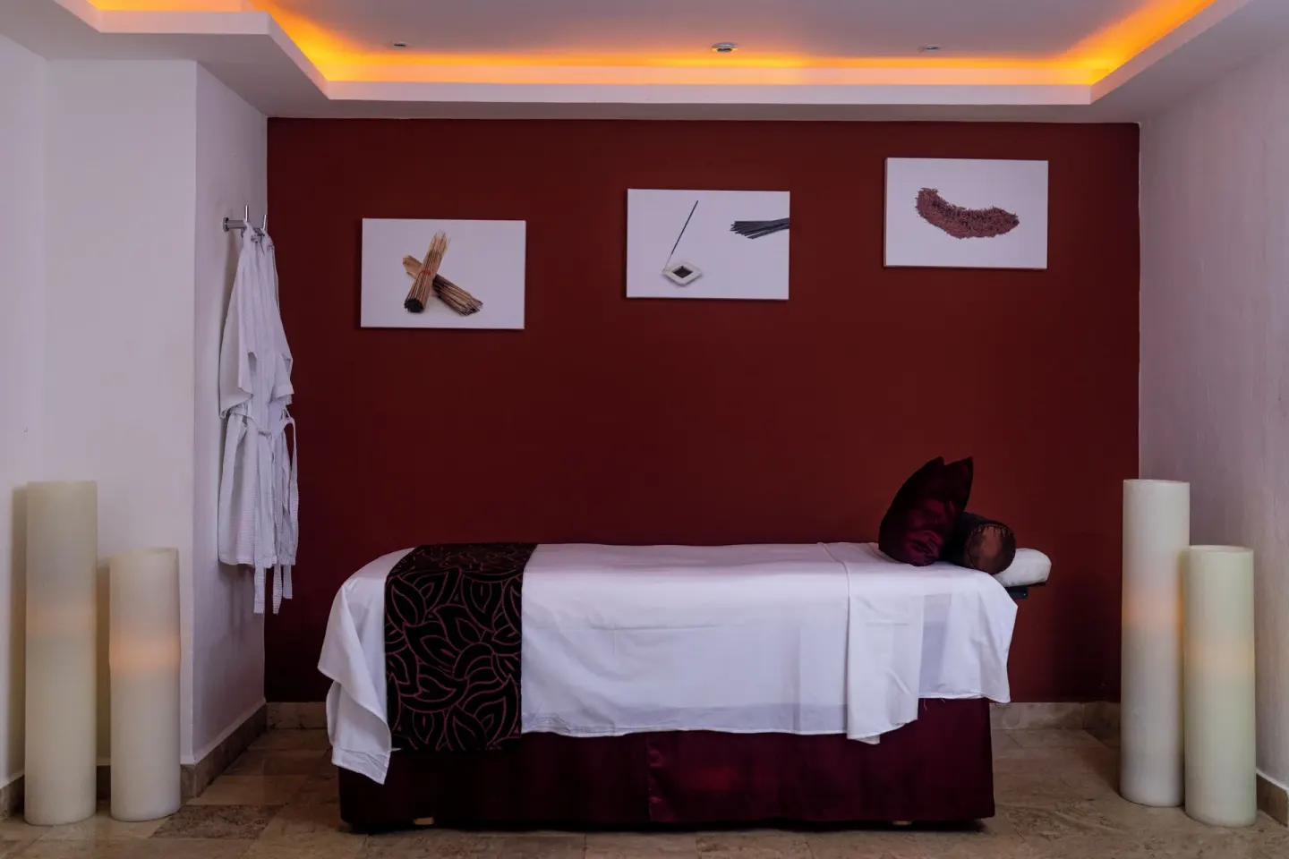 A spa treatment room with a massage bed and robe at Valentin Imperial Riviera Maya.