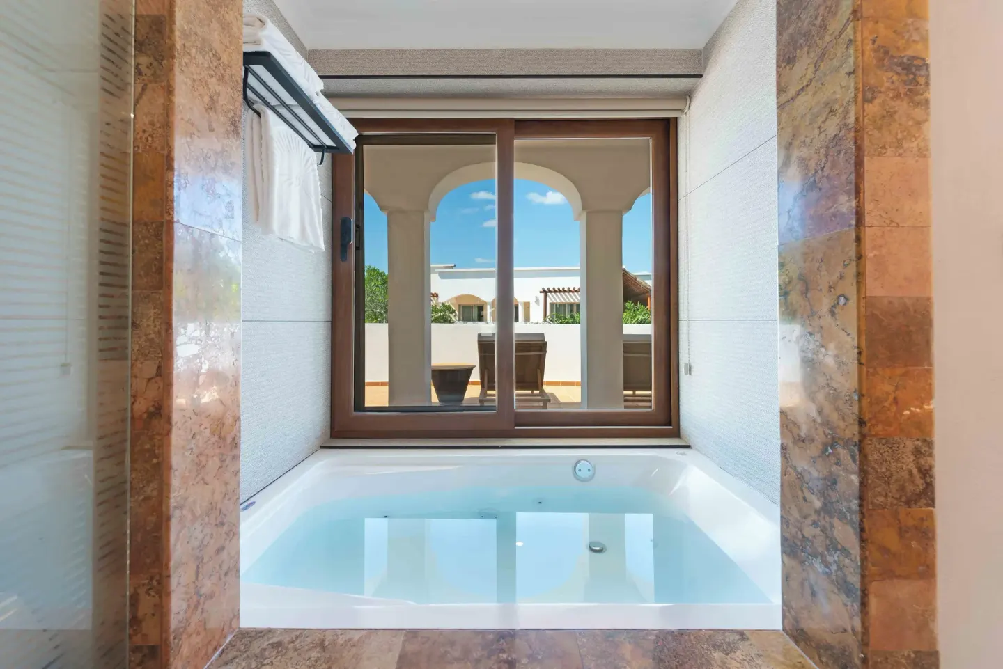 Bathroom soaking tub beside a terrace window at Valentin Imperial Riviera Maya.