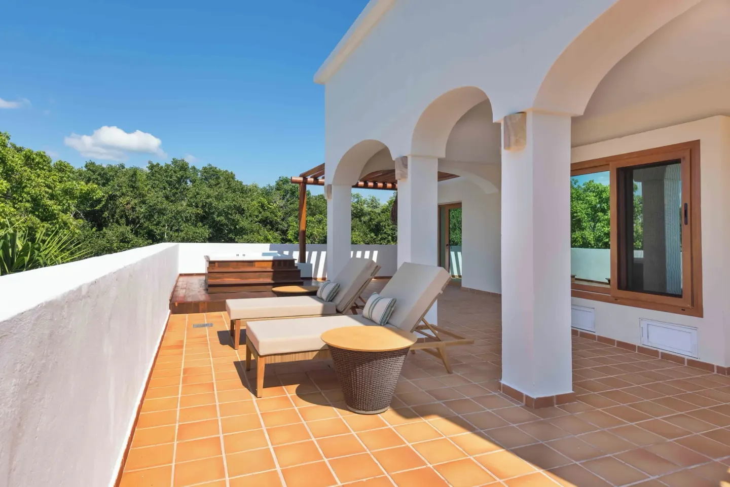 Sunny terrace with lounge chairs and arched colonnade at Valentin Imperial Riviera Maya.