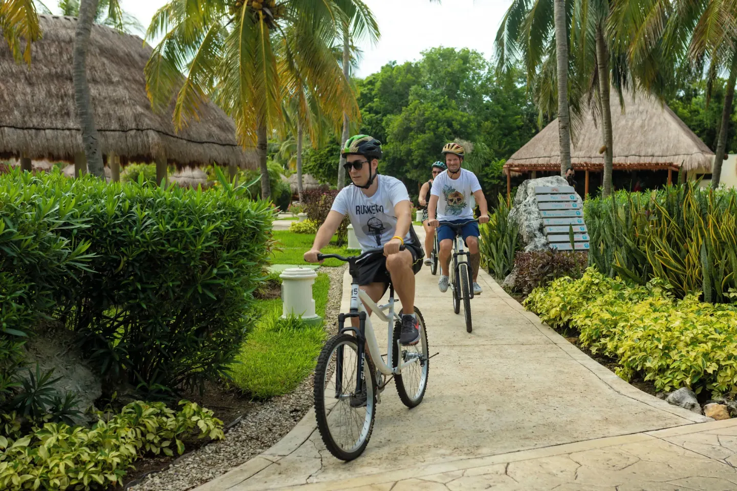 Guests bike along a tropical garden path at Valentin Imperial Riviera Maya.