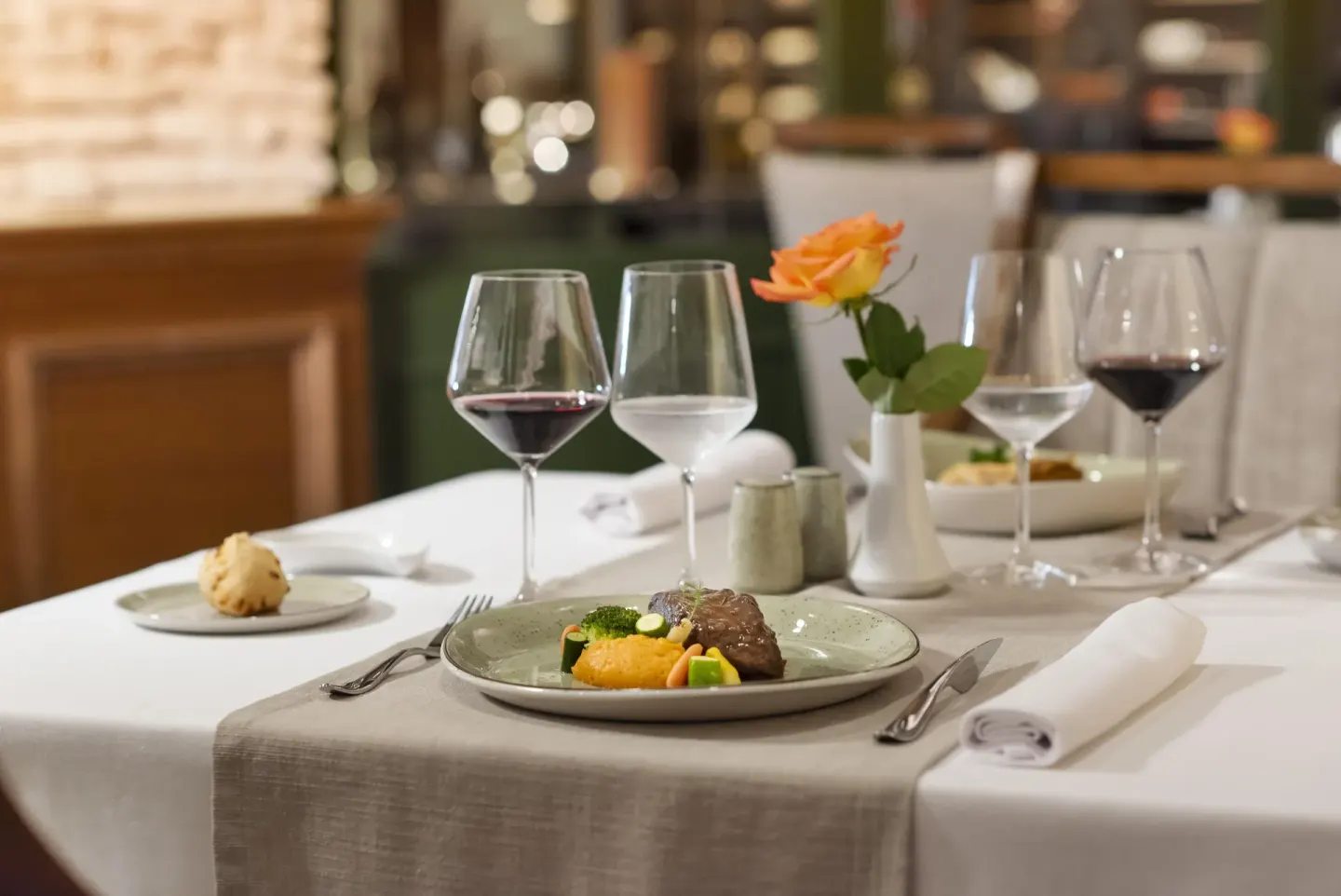 Plated dinner with wine glasses on a white table at Valentin Imperial Riviera Maya.