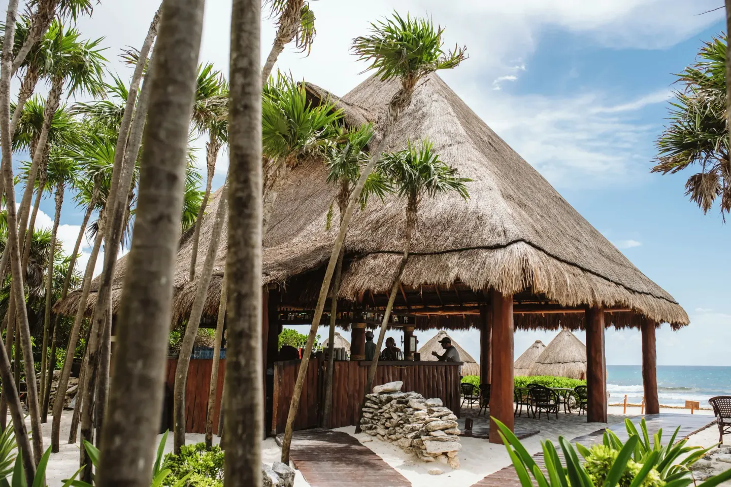 Thatched beachfront bar among palms at Valentin Imperial Riviera Maya.