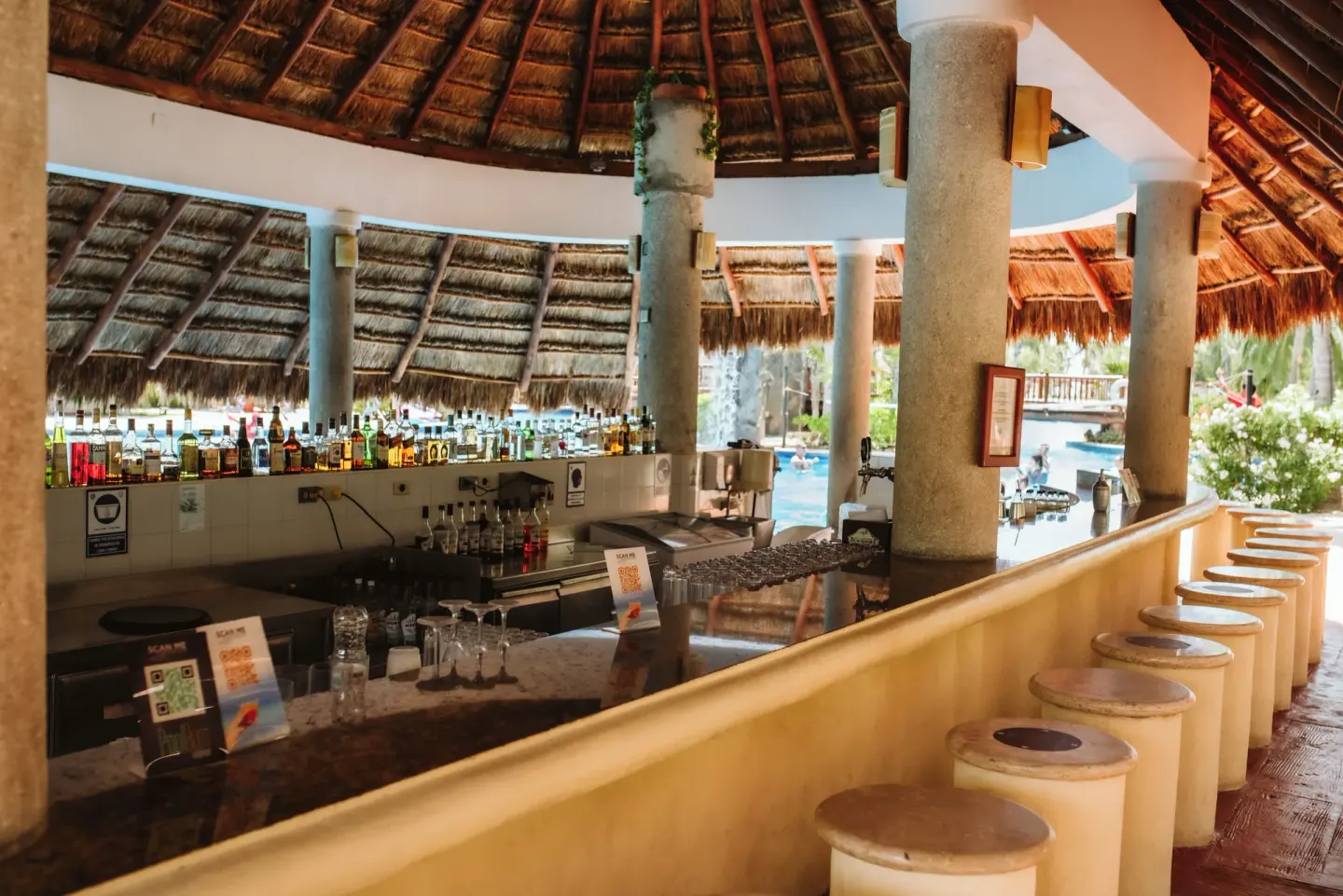 Thatched swim-up bar with stools and bottles at Valentin Imperial Riviera Maya.