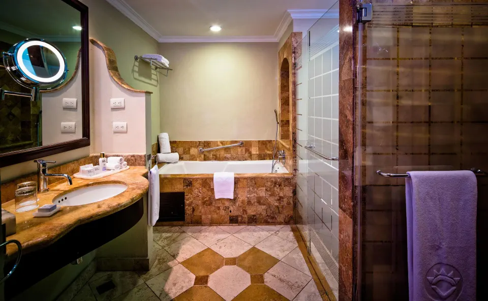 Deluxe Junior Suite bathroom with tub, vanity, and glass shower at Valentin Imperial Riviera Maya.