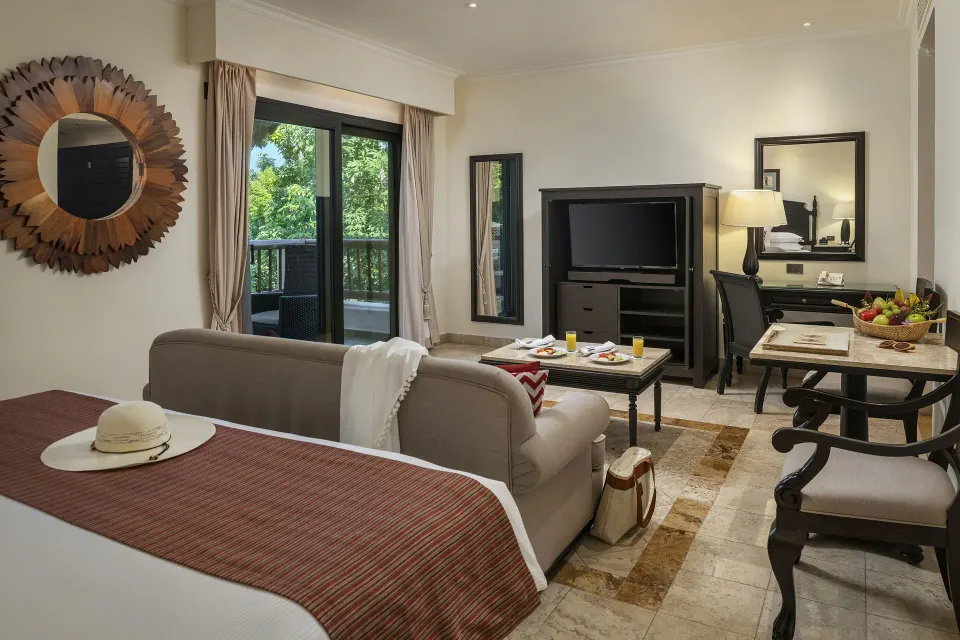 Deluxe Junior Suite garden-view room with bed, TV, and balcony doors at Valentin Imperial Riviera Maya.