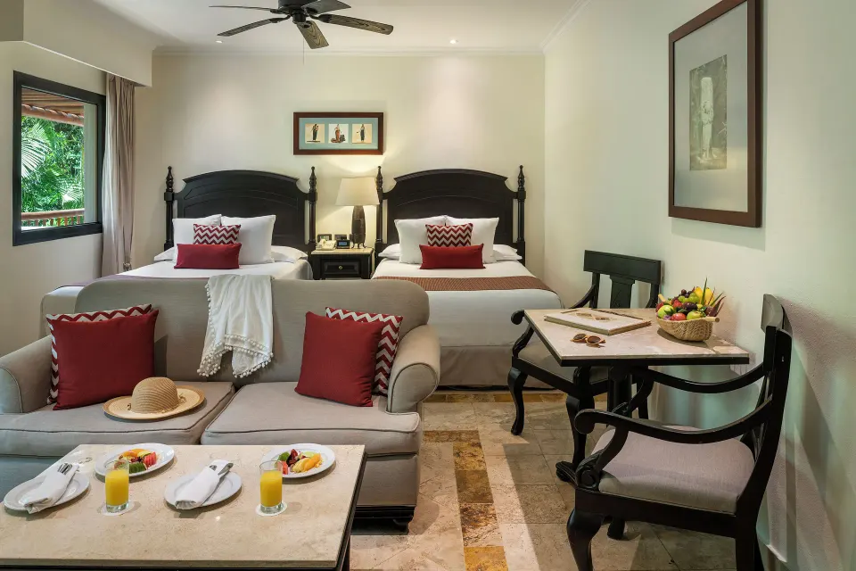 Deluxe Junior Suite garden-view room with two beds and sitting area at Valentin Imperial Riviera Maya.