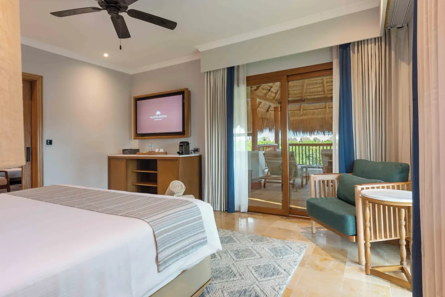 Diamond Suite bedroom with bed, seating, TV, and balcony at Valentin Imperial Riviera Maya.