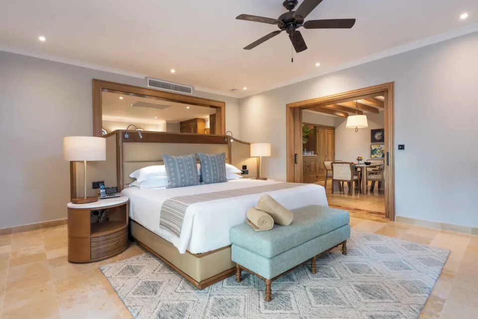 Diamond Suite king bed with sitting bench and dining area at Valentin Imperial Riviera Maya.