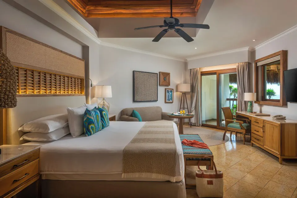Emerald Junior Suite king bed, sofa, desk, and balcony at Valentin Imperial Riviera Maya.