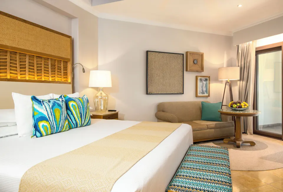 Emerald Junior Suite king bed, sofa, and balcony door at Valentin Imperial Riviera Maya.