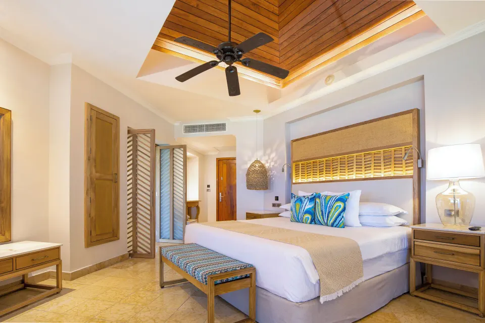 Emerald Junior Suite king bed under wood ceiling fan at Valentin Imperial Riviera Maya.