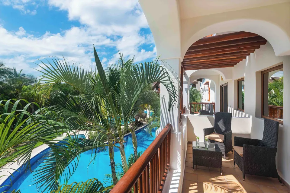 Golden Junior Suite balcony overlooking pool and palms at Valentin Imperial Riviera Maya.