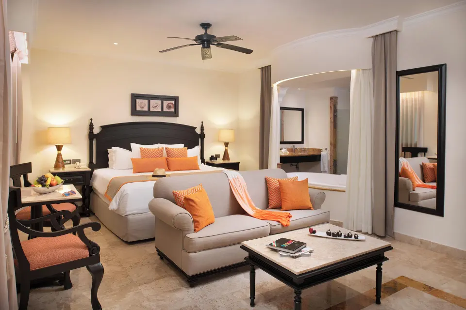 Silver Junior Suite king bed with orange accents and sofa at Valentin Imperial Riviera Maya.