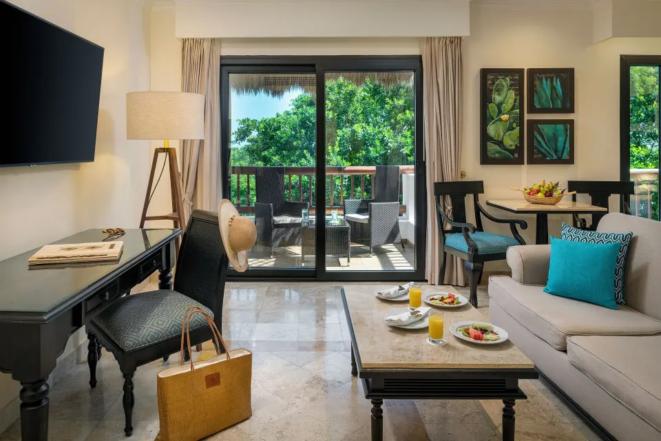 Silver Junior Suite lounge, desk, dining table, and balcony at Valentin Imperial Riviera Maya.