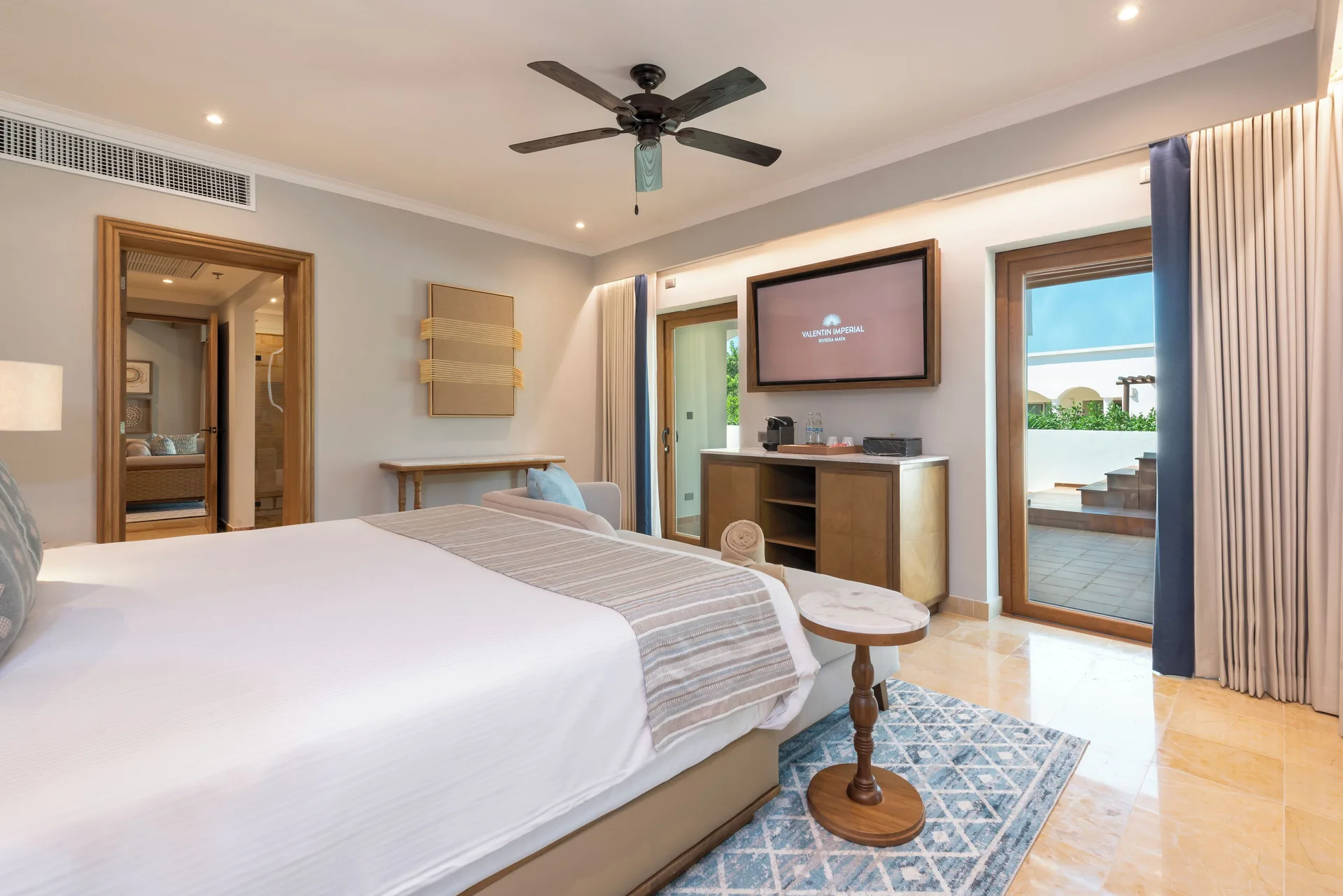 Onyx Honeymoon Suite bedroom with TV, king bed, and terrace doors at Valentin Imperial Riviera Maya.