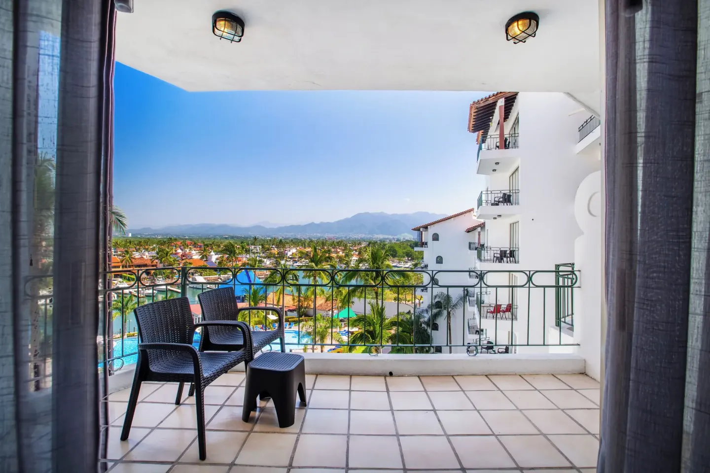 Balcony with chairs overlooking pools and mountains at Vamar Vallarta Marina and Beach Resort.