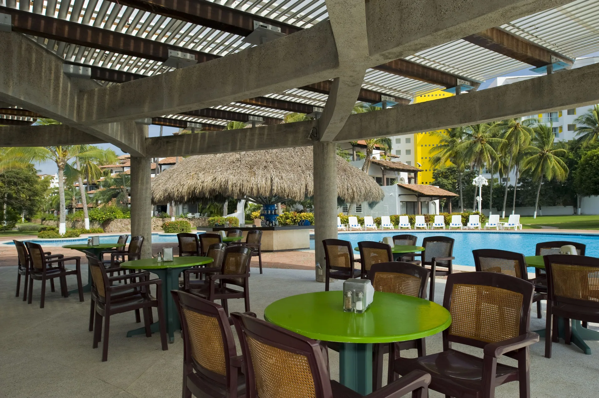 Poolside tables under a pergola at Vamar Vallarta Marina and Beach Resort.