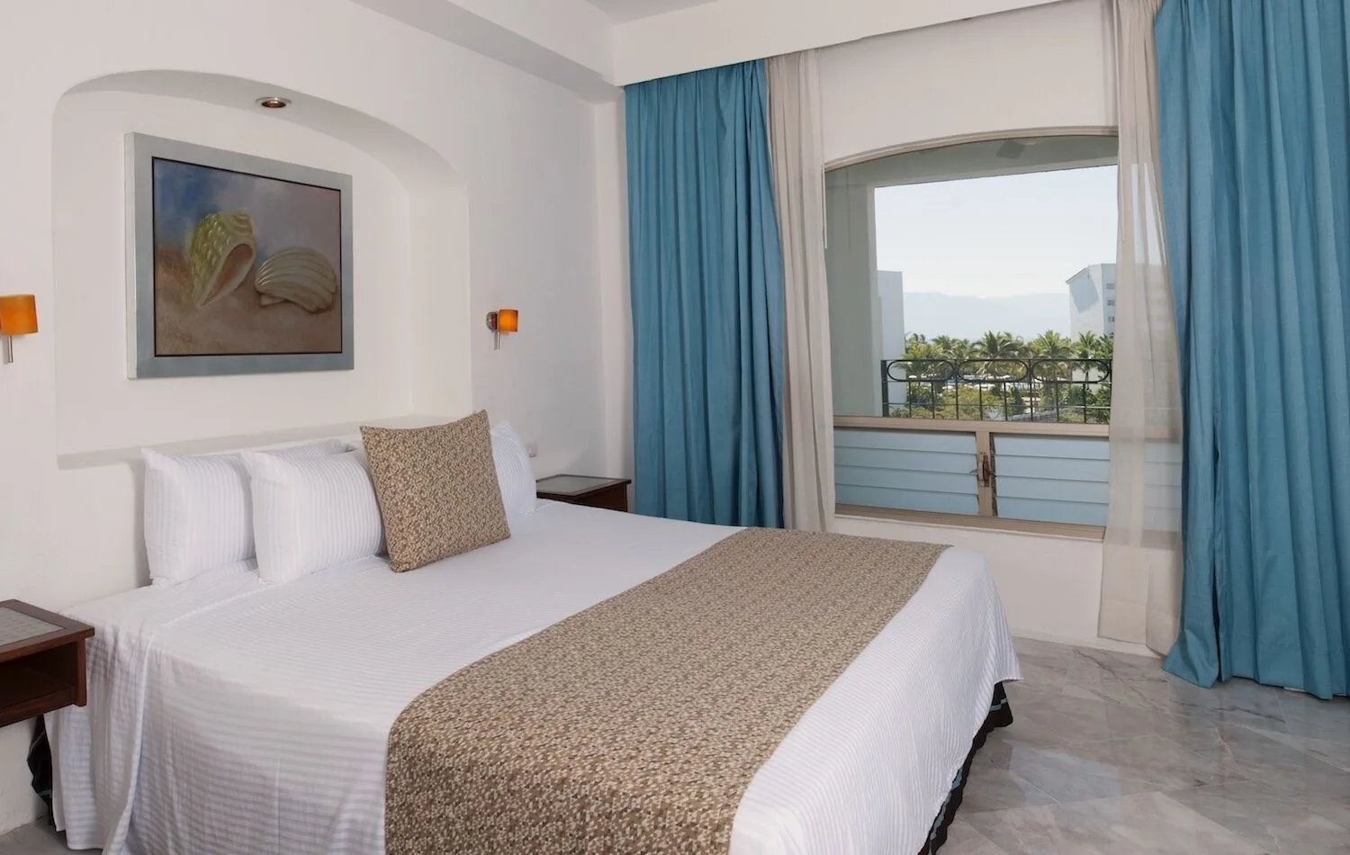 Standard king room with blue curtains and balcony at Vamar Vallarta Marina and Beach Resort.