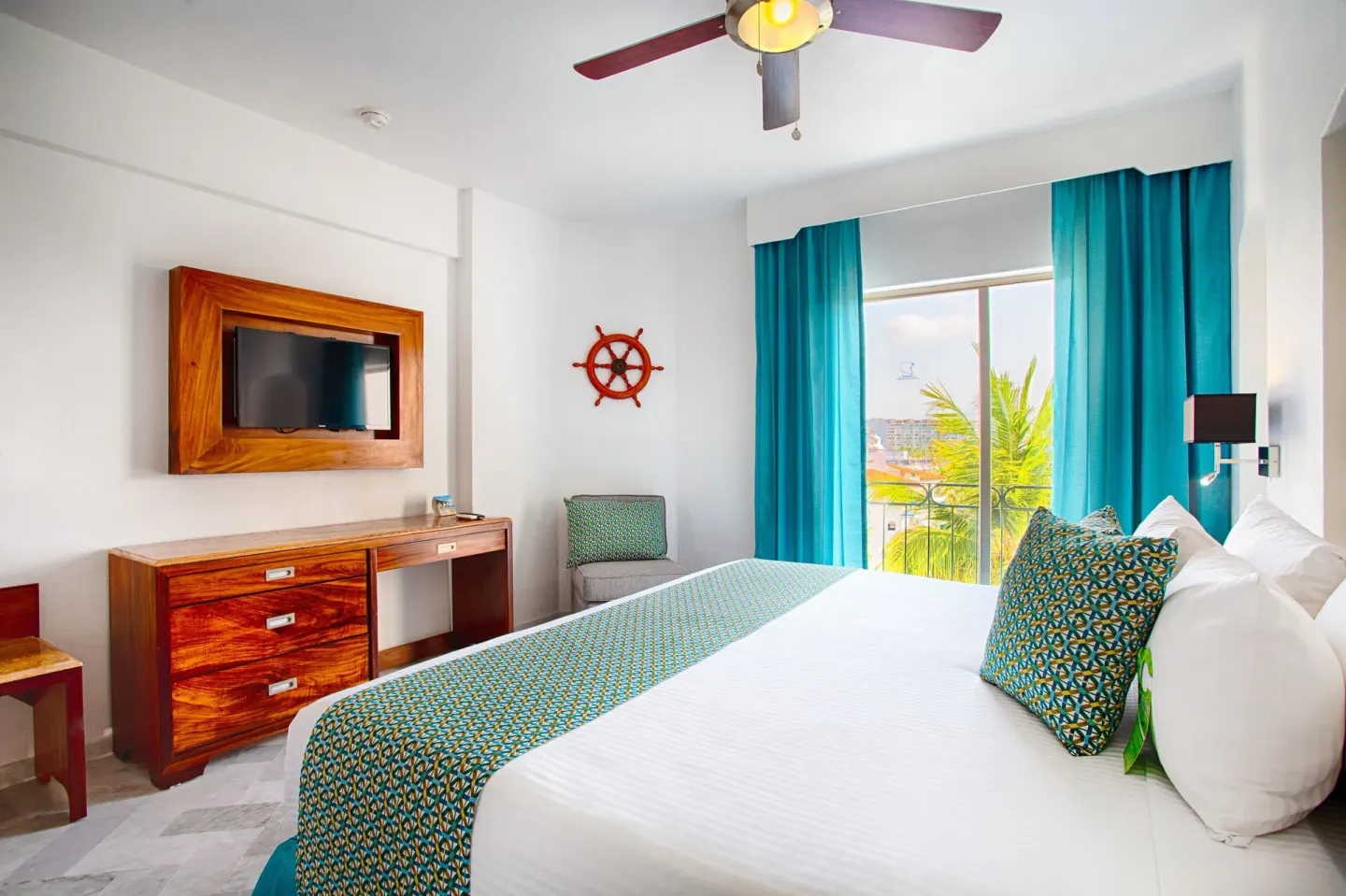 Standard king room with TV, desk, ceiling fan, and turquoise accents at Vamar Vallarta Marina and Beach Resort.