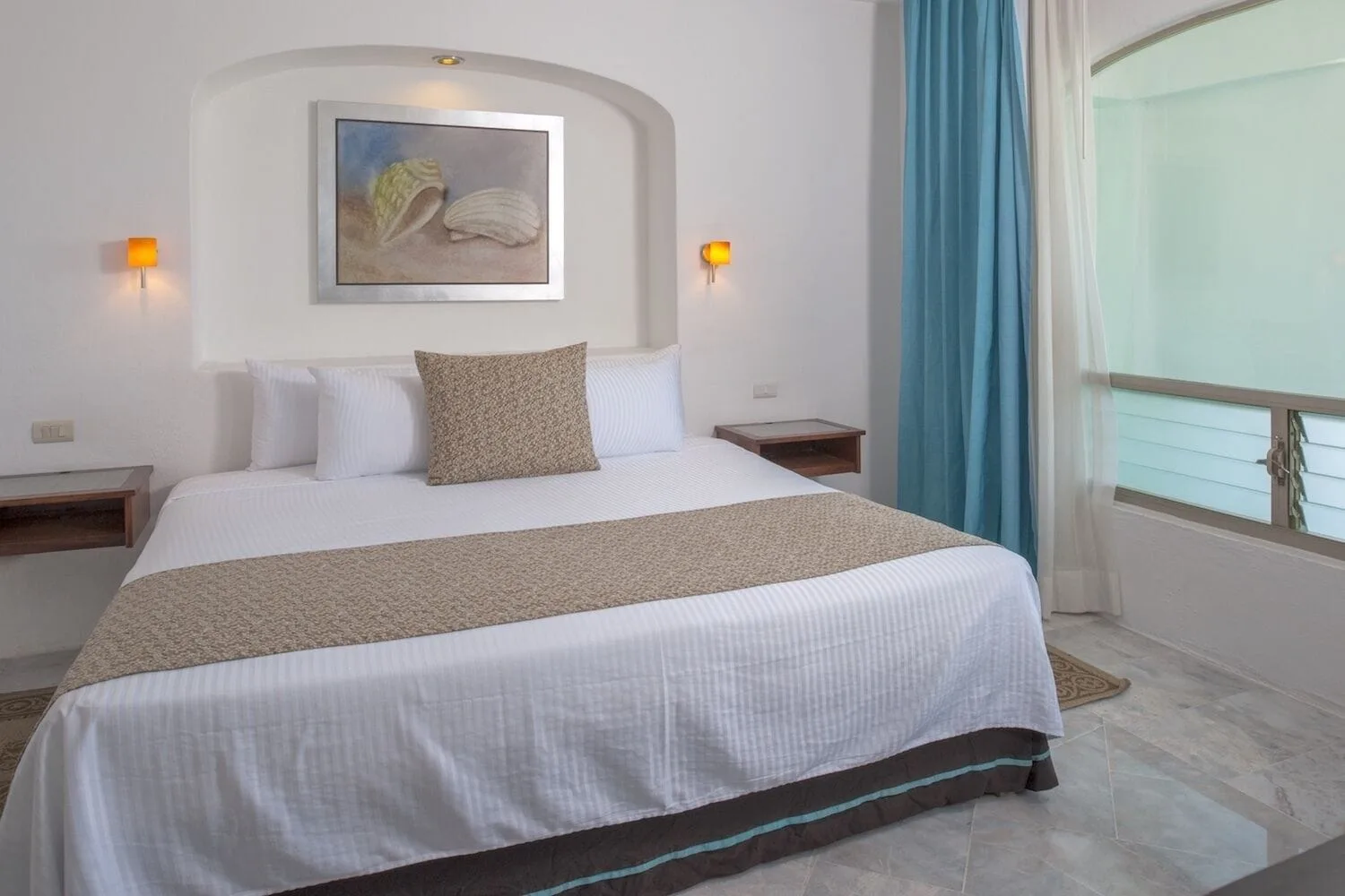 Standard king room with shell artwork and balcony curtains at Vamar Vallarta Marina and Beach Resort.
