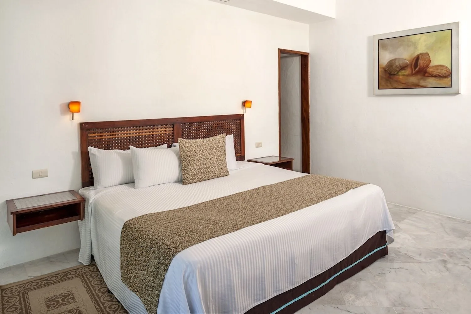 Standard king room with woven headboard and shell artwork at Vamar Vallarta Marina and Beach Resort.