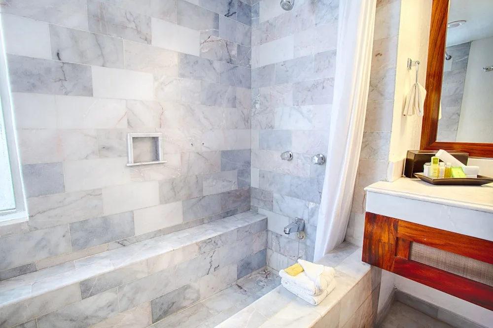 Standard room bathroom shower with gray tile and vanity edge at Vamar Vallarta Marina and Beach Resort.