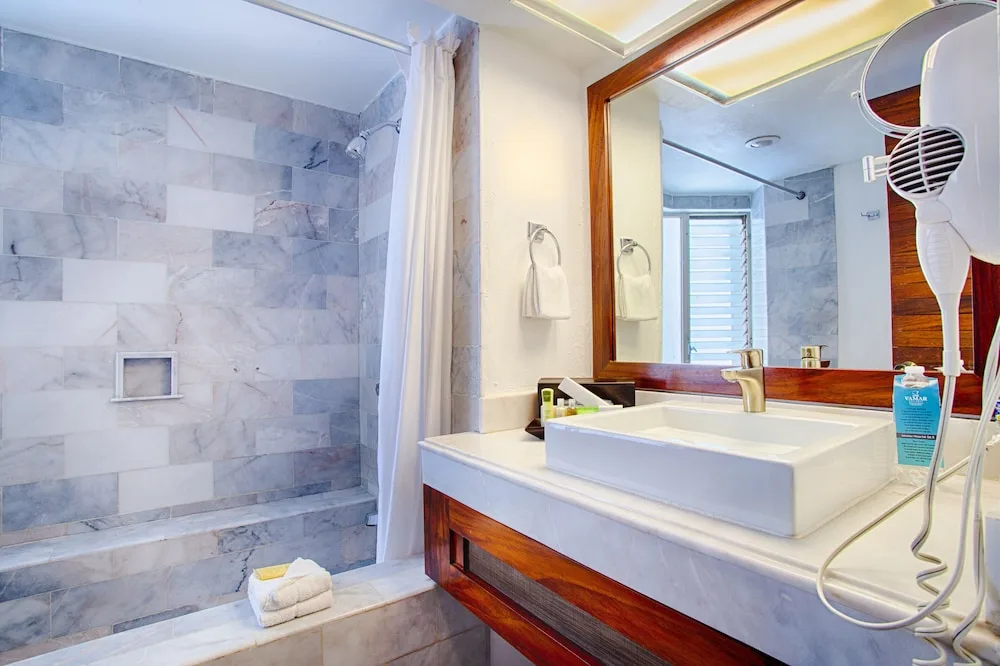 Standard room bathroom with marble-tile shower and square sink at Vamar Vallarta Marina and Beach Resort.