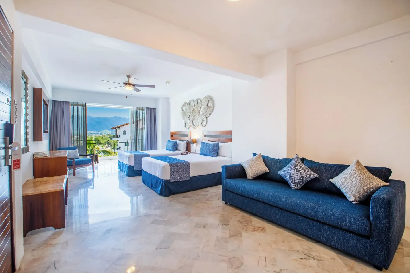 Superior Con Balcón room with two beds and blue sofa at Vamar Vallarta Marina and Beach Resort.