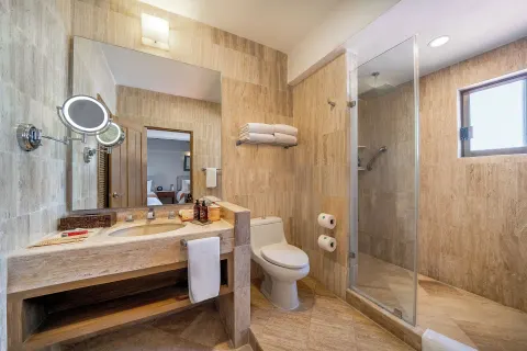 Bathroom with vanity, toilet, and glass shower at Velas Vallarta Suites Resort.