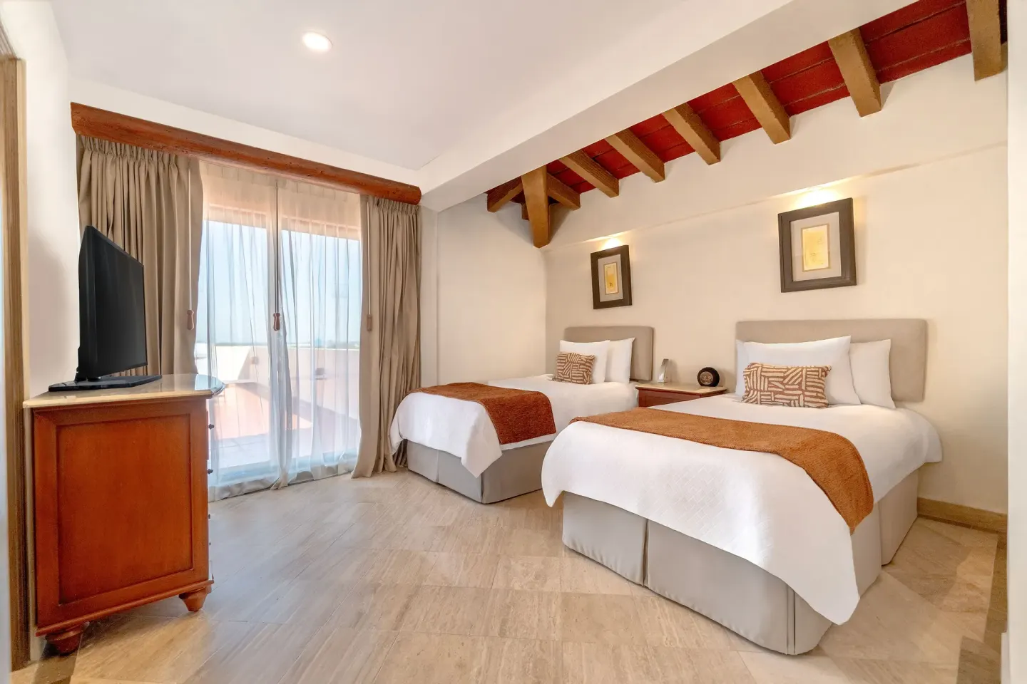 Two twin beds, TV, and balcony doors in a guest room at Velas Vallarta Suites Resort.