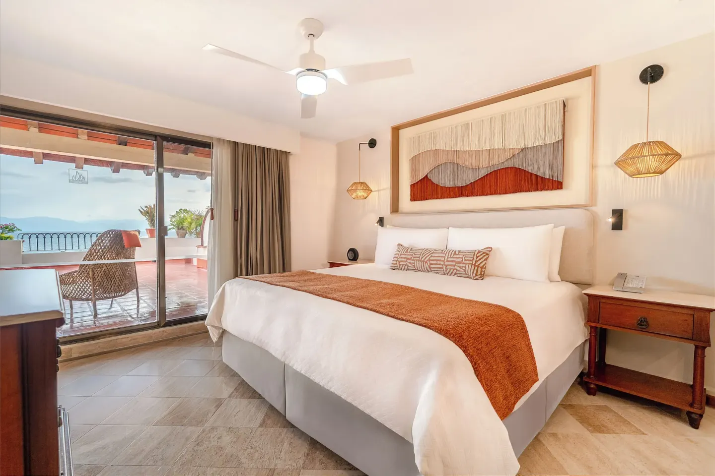 King bed guest room with ocean-view balcony at Velas Vallarta Suites Resort.