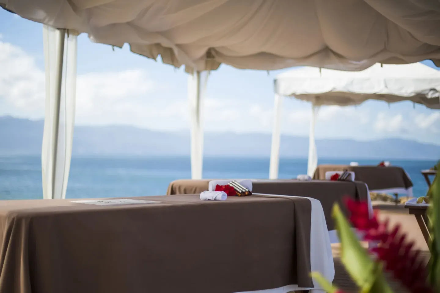 Oceanfront massage tables under white canopies at Velas Vallarta Suites Resort.
