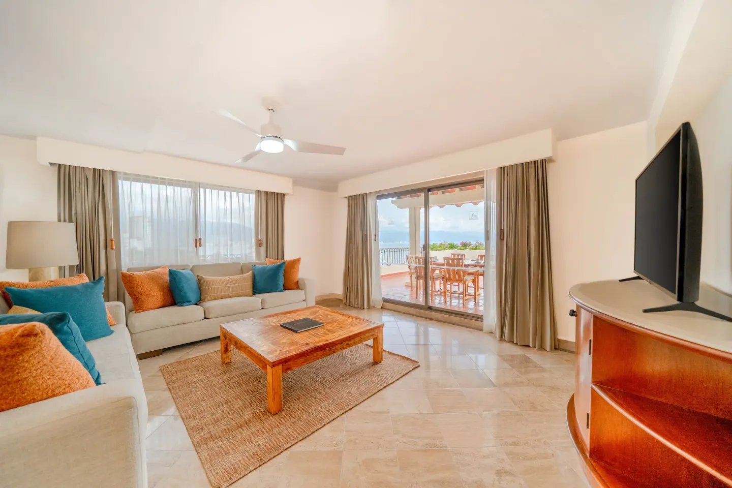 Suite living room with sofas, TV, and balcony seating at Velas Vallarta Suites Resort.
