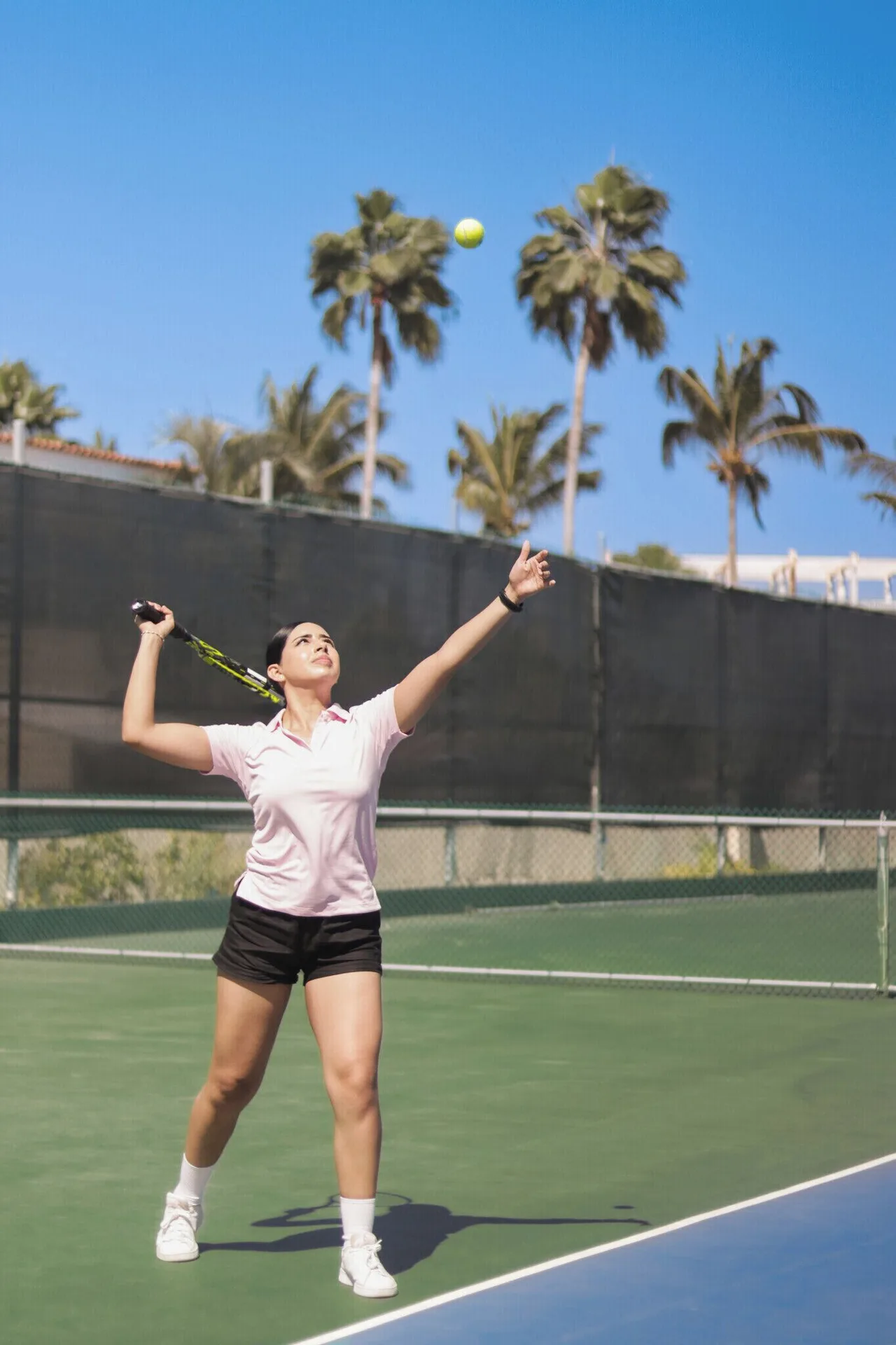 A tennis player serves on an outdoor court at Velas Vallarta Suites Resort.