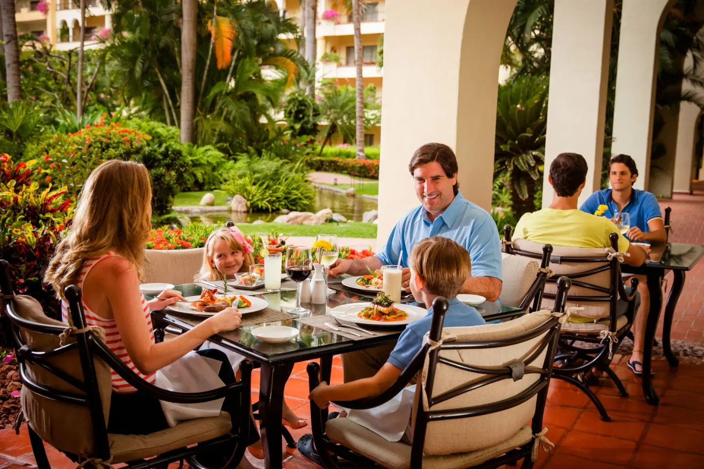 A family eats on a garden terrace at Velas Vallarta Suites Resort.