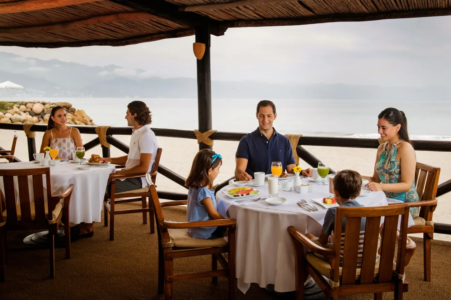 Families dine on an oceanfront terrace at Velas Vallarta Suites Resort.