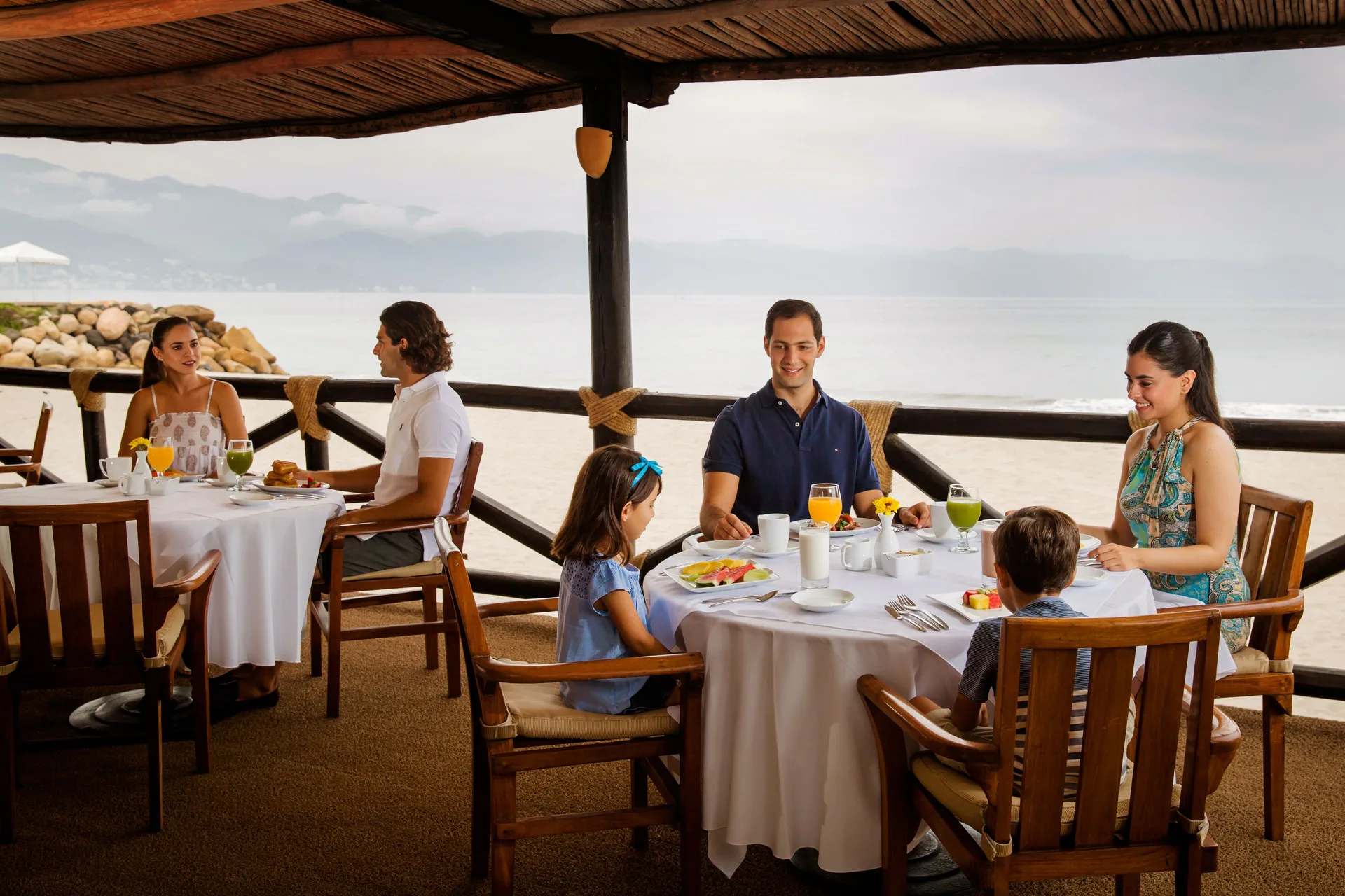 Families dine on an oceanfront terrace at Velas Vallarta Suites Resort.
